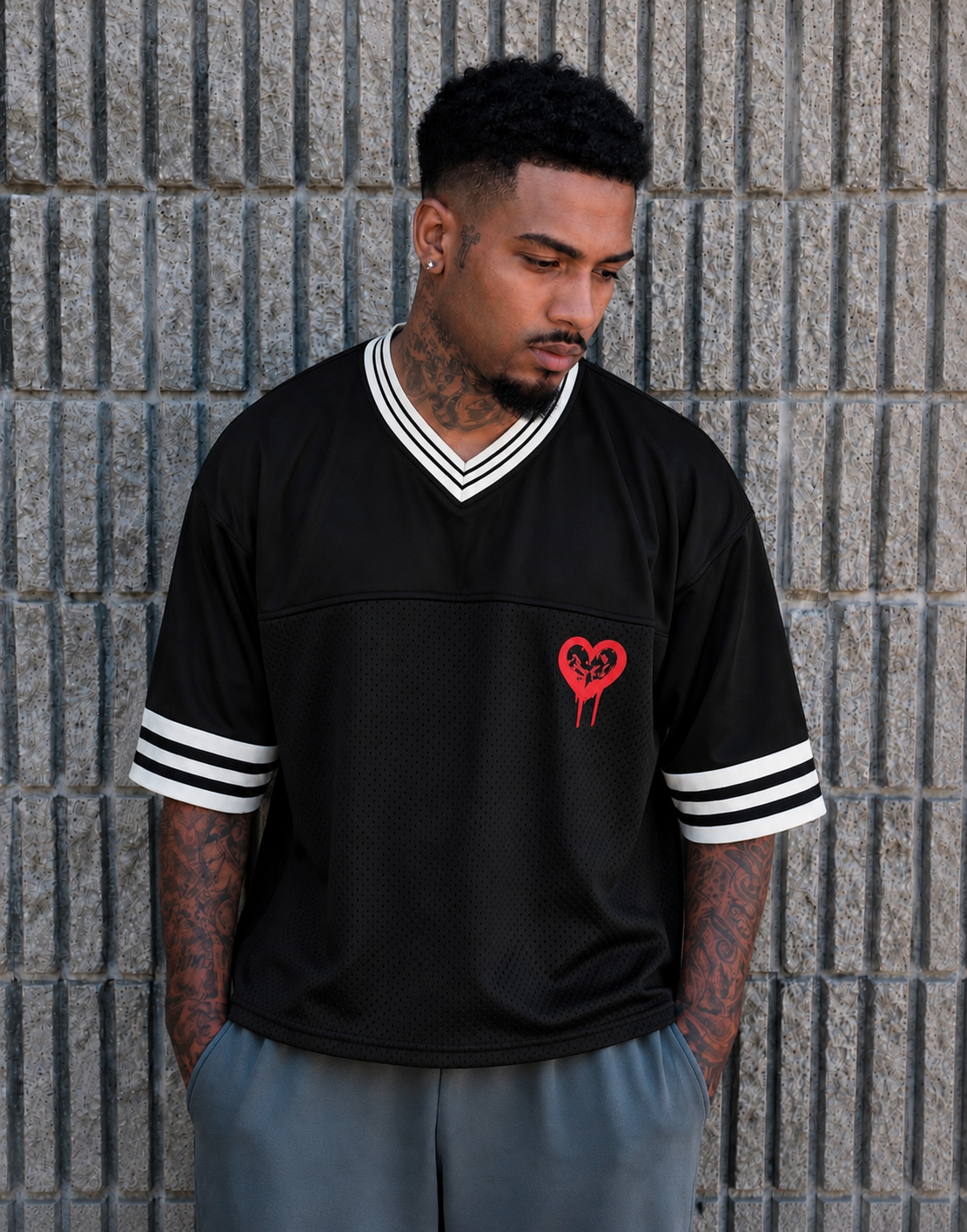 God & Grit black oversized mesh jersey with a red heart graphic, V-neck, and striped ribbed trim on sleeves.