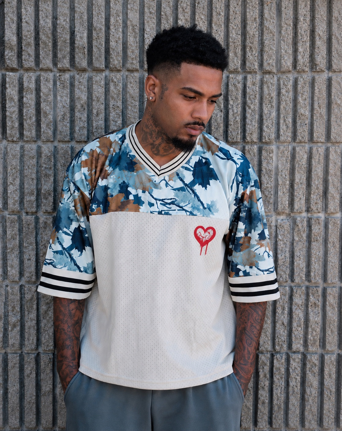 God & Grit oversized mesh jersey with camouflage pattern, heart graphic, and striped ribbed V-neck on a male model.