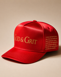 God & Grit red satin baseball cap featuring gold embroidered branding and scripture text on the side panel